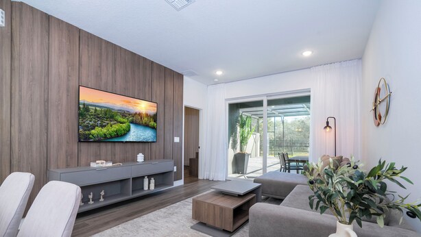 A modern living room with a flat-screen TV, grey sofas, a coffee table, and a plant. - Doppio Westside (Davenport)
