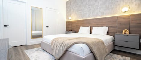 A modern bedroom with a large bed, bedside tables, a wardrobe, and a mirror.