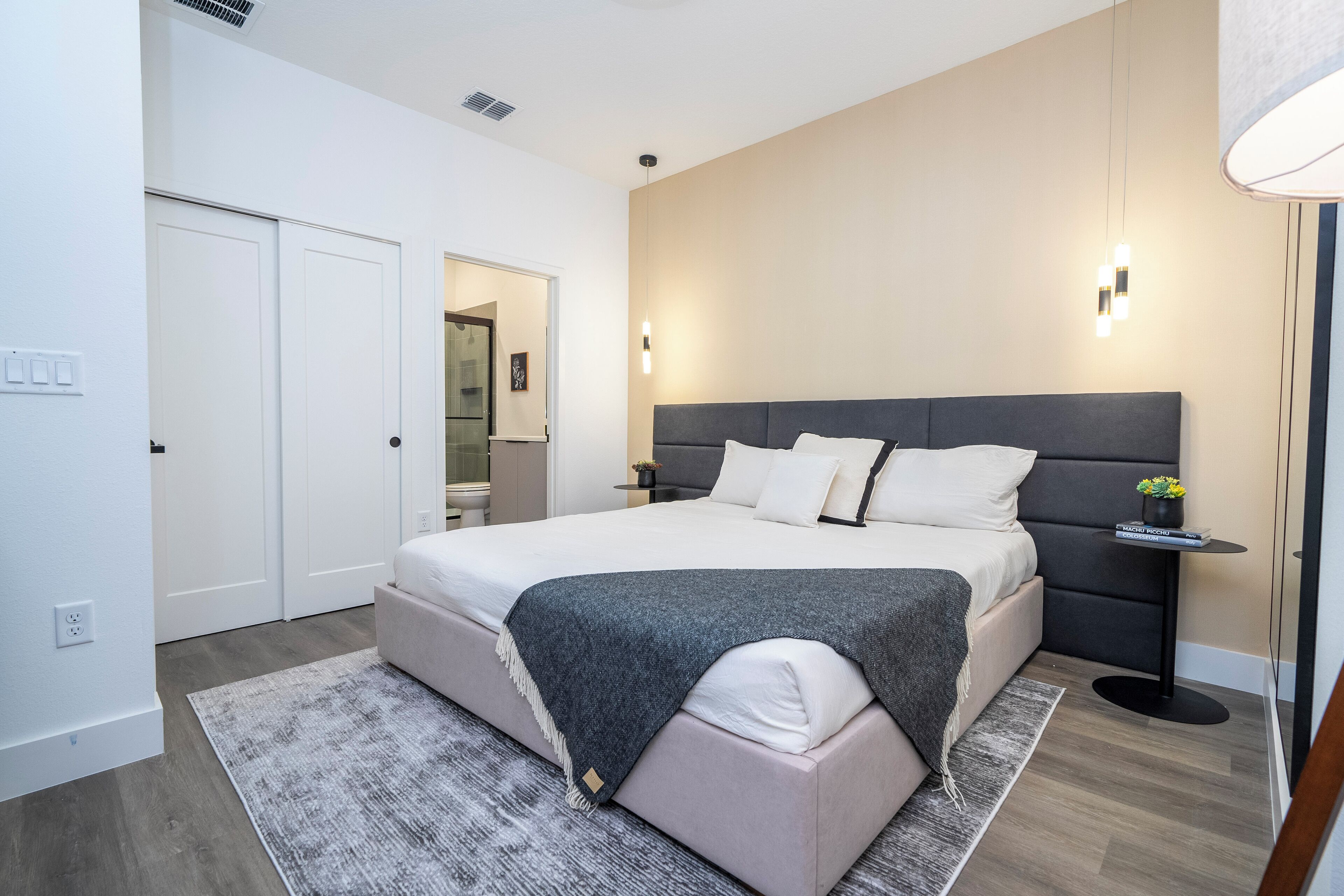 A modern bedroom with a large bed, bedside tables, and a nightstand with a lamp.