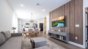 A modern living room with a gray sofa, a coffee table, and a TV mounted on a wooden wall. - Doppio Westside (Davenport)