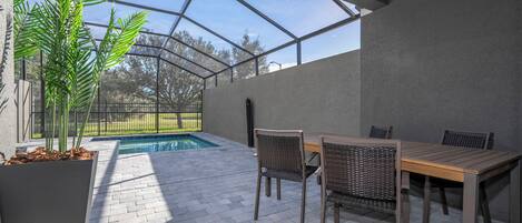 A covered patio area with a pool, outdoor furniture, and a large potted plant.