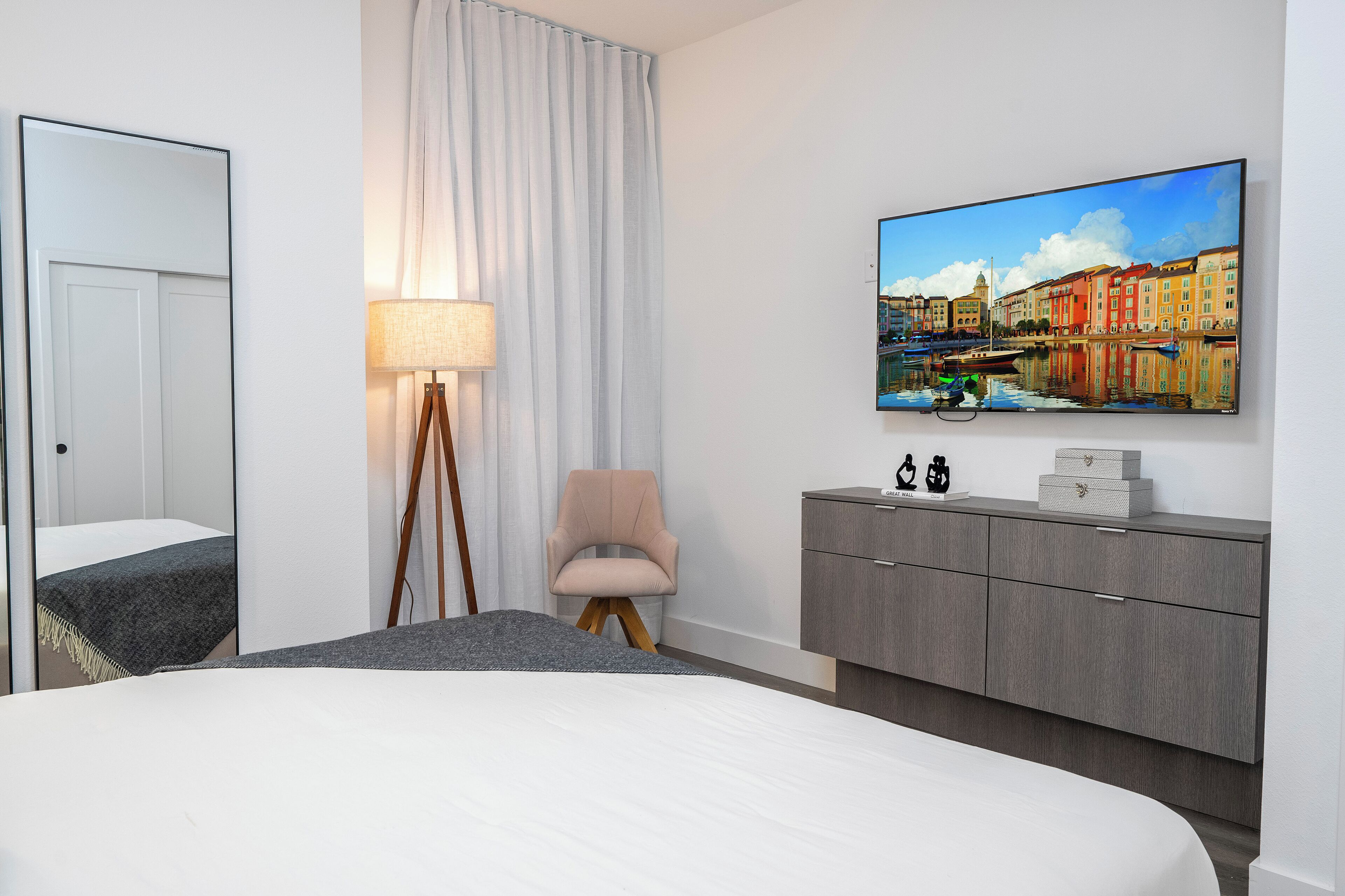 Una moderna camera d'albergo con un letto grande, una scrivania, una sedia, una TV a parete e vista sulla città.