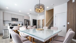 A modern kitchen with stainless steel appliances, a glass dining table, and contemporary chairs. - Doppio Westside (Davenport)