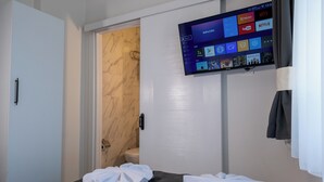 A hotel room with a bed, a TV mounted on the wall displaying various streaming services, and a bathroom door. - Sweet Hotel Istanbul (Istanbul)