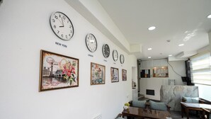 A hotel lobby with multiple clocks displaying different time zones, a seating area with wooden tables and chairs, and a wall decorated with framed pictures. - Sweet Hotel Istanbul (Istanbul)