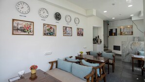 A hotel room with a dining area, a sofa, a coffee table, and a kitchen area. There are clocks on the wall displaying different cities. - Sweet Hotel Istanbul (Istanbul)