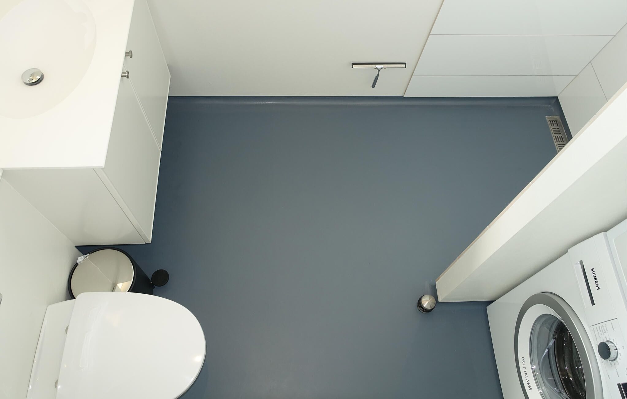 Un bagno con lavandino bianco, water e lavatrice.