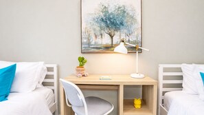 A hotel room with two beds, a desk with a lamp, a small plant, and a painting on the wall. - Modern Spacious 5BR Retreat - Games & Large Yard (San Jose)