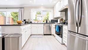 Una cocina moderna con electrodomésticos de acero inoxidable, armarios blancos y vistas al exterior.