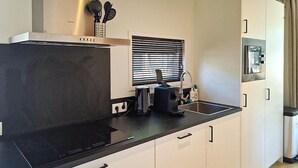 A compact kitchen with a built-in stove, a coffee maker, and a window with blinds. - Stunning home in Hellendoorn with WiFi (Hellendoorn)