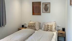 A bedroom with two beds, patterned pillows, a nightstand with a lamp, and two framed artworks on the wall. - Stunning home in Hellendoorn with WiFi (Hellendoorn)