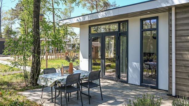 A modern outdoor patio with a table and chairs, surrounded by glass doors and a garden. - Stunning home in Hellendoorn with WiFi (Hellendoorn)