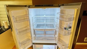 Avoin jääkaappi, jossa on useita hyllyjä ja erillinen pakastinosa.