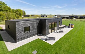 A modern house with a flat roof, large windows, and a patio area with outdoor furniture. - Awesome home in Grenaa with sauna (Grenaa)