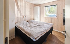 A small, compact room with a bed, a wardrobe, and a window.