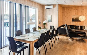 A modern dining area with a wooden table, black chairs, and a black sofa.