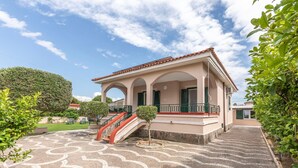 A building with a tiled roof, a staircase, and a paved courtyard with a geometric pattern.
