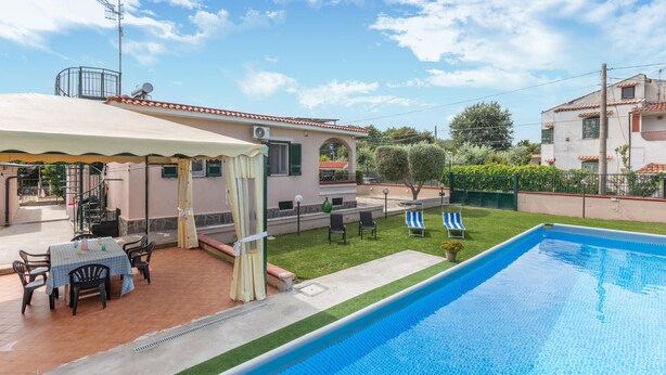 A swimming pool with a covered patio area, outdoor seating, and a view of neighboring houses.