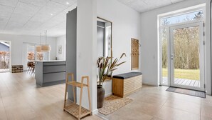 A spacious, modern interior with a large sliding glass door leading to an outdoor area, a wooden bench, and a small wooden shelf. - 3 bedroom lovely home in Ebeltoft (Ebeltoft)
