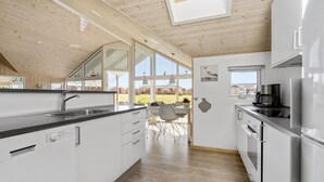 A modern kitchen with a large island, white cabinetry, and a view of the outdoors.