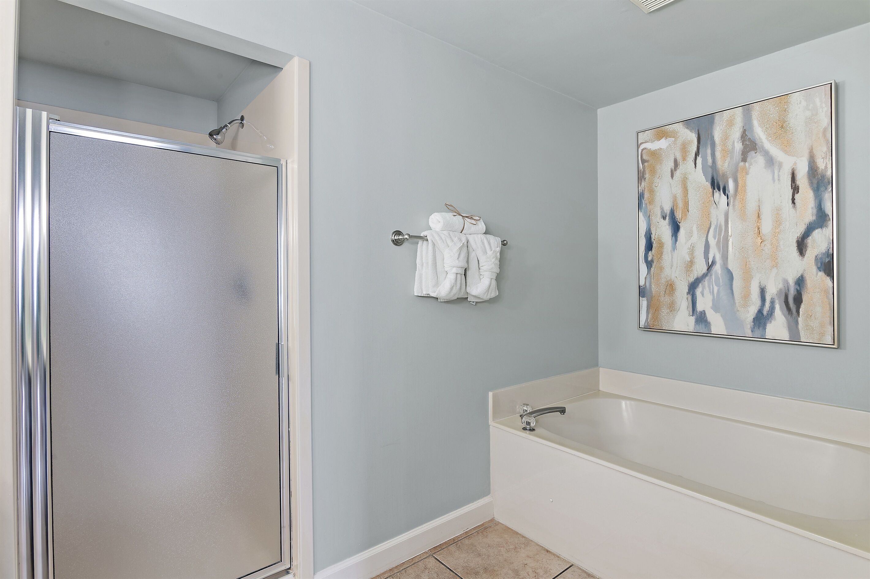 A bathroom with a shower, a bathtub, and a towel rack with towels.