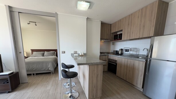 Una cocina moderna con armarios de madera, un refrigerador de acero inoxidable y una barra desayunadora.