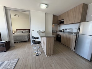 Une cuisine moderne avec des meubles en bois, un réfrigérateur en acier inoxydable et un bar pour prendre le petit-déjeuner.