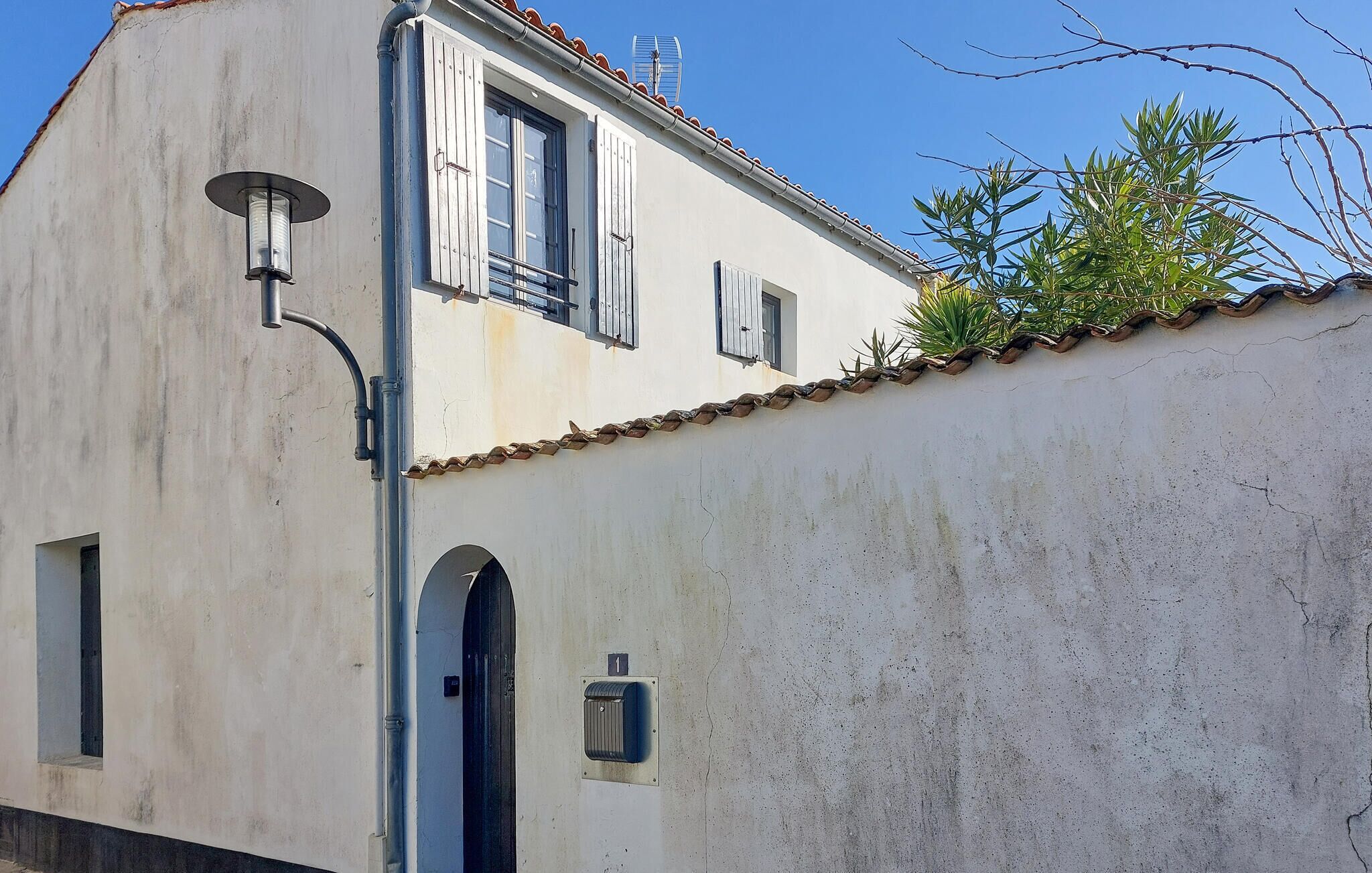 A building with a white facade, a tiled roof, and a small window with shutters.