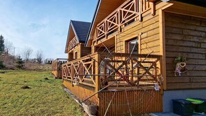 Een houten chalet met balkon en omheind terras.