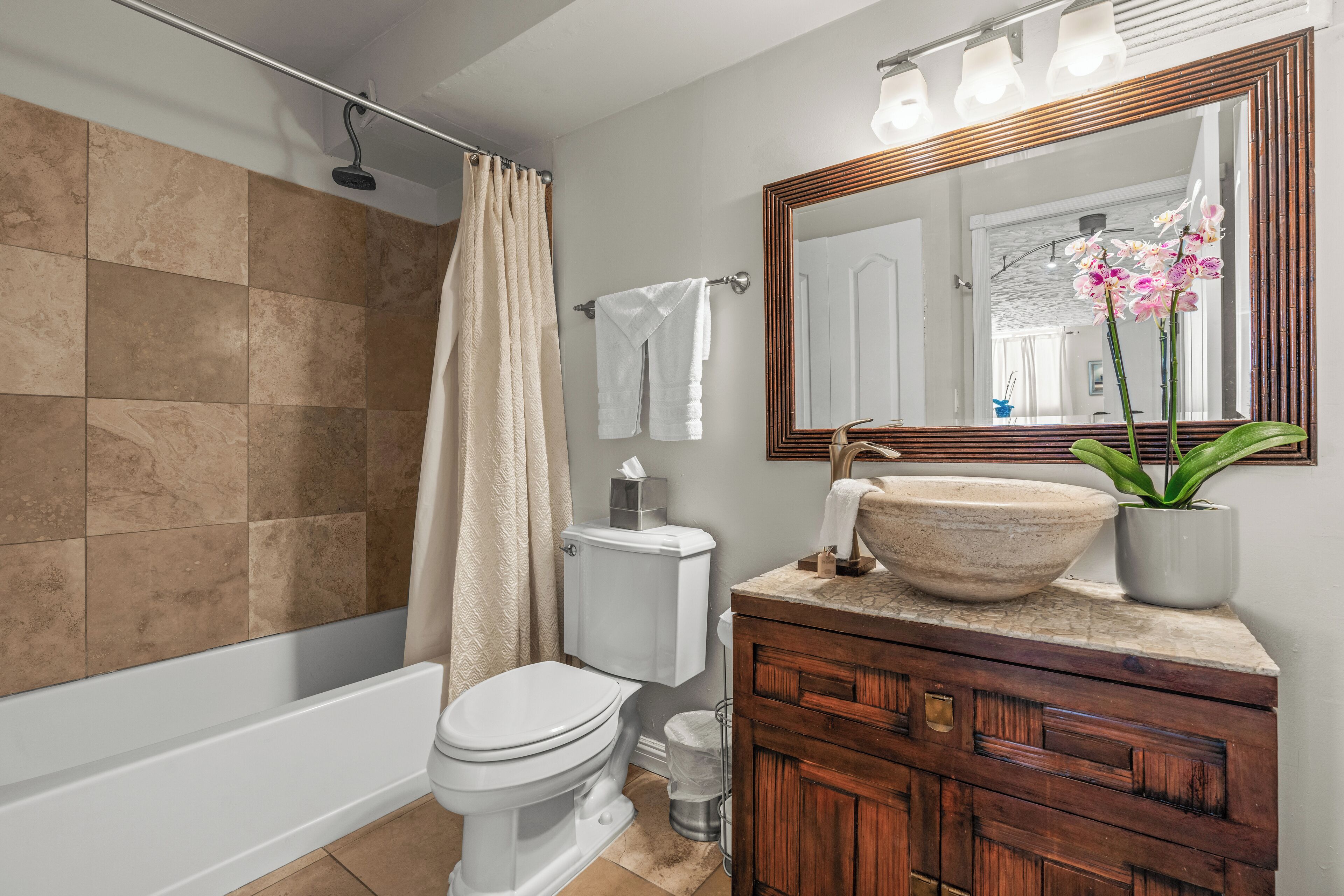 A bathroom with a bathtub, toilet, and vanity with a large mirror.