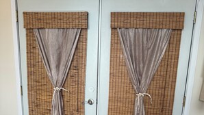 A set of double doors with a grid-patterned window covering and curtains tied at the bottom. - Ocean View Mid Waikiki 1 Block to the Beach (Honolulu)
