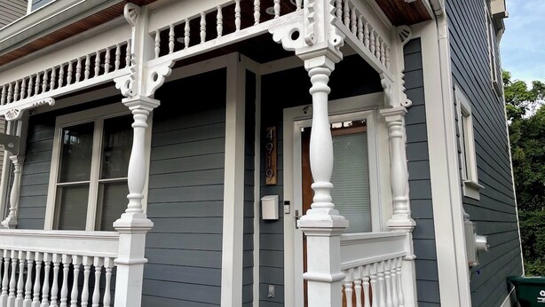 Una casa con un portico caratterizzato da balaustre bianche e un tetto in legno.