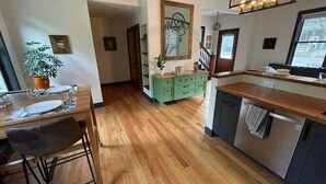 Una cucina moderna con pavimento in legno, un'area pranzo con uno sgabello da bar e un armadietto verde.