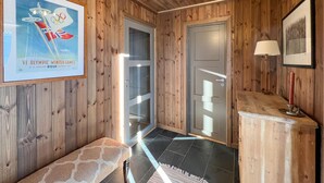 A wooden interior with a bench, a framed poster, a door, and a small table with a candle. - Cozy home in Sjusjøen with sauna (Sjusjøen)