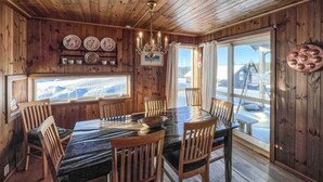 A wooden interior with a dining table and chairs, a chandelier, and a view of a snowy landscape through large windows. - Cozy home in Sjusjøen with sauna (Sjusjøen)