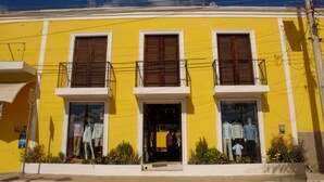 Un bâtiment jaune avec trois fenêtres et une devanture de magasin.