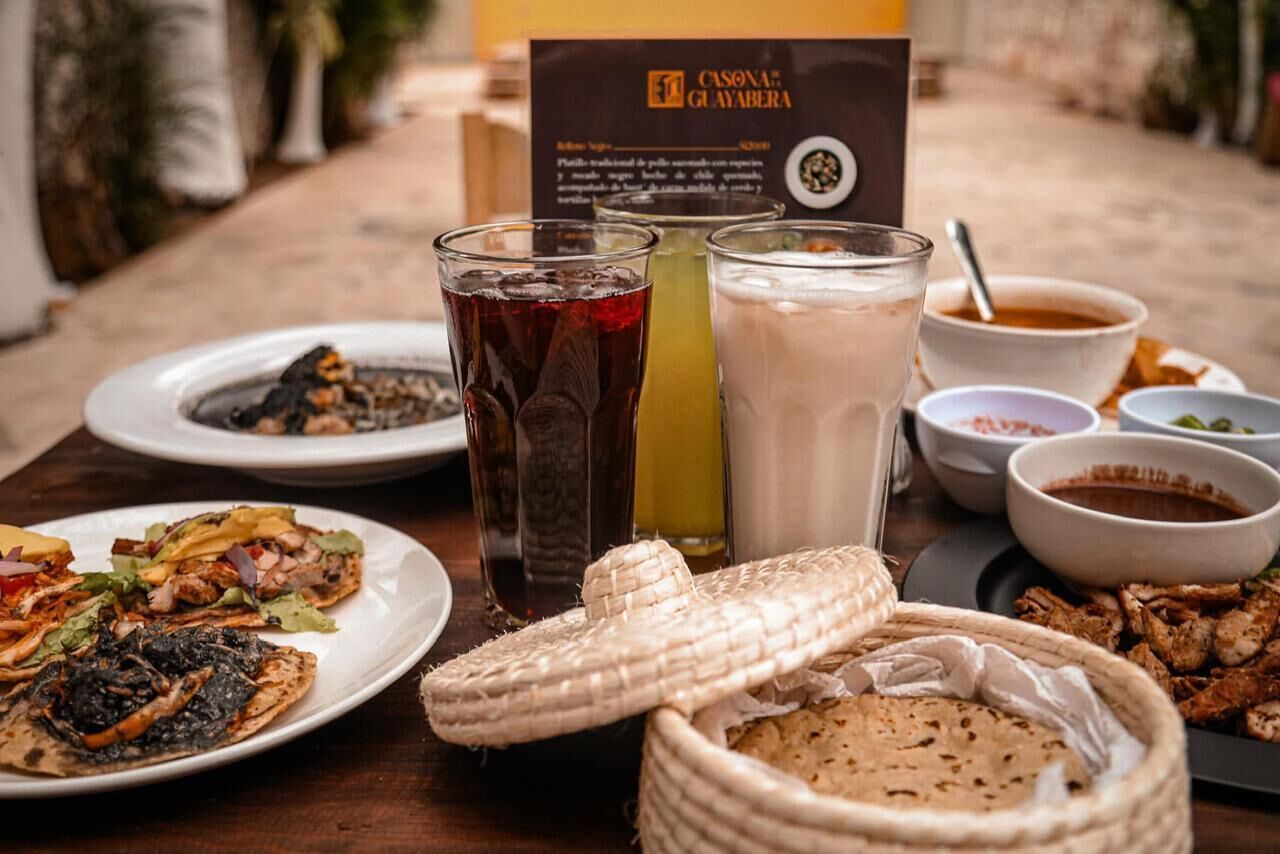 A table with various dishes, drinks, and a menu at a restaurant.