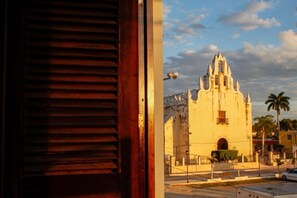 Une vue d’un bâtiment historique doté d’un clocher, d’une rue pavée et d’un palmier au premier plan.