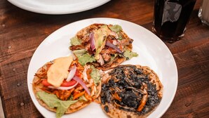 Une assiette contenant trois tacos, posée sur une table en bois.