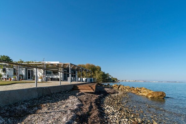 A modern building with a covered walkway leading to a rocky shoreline by the sea. - Seaside Private Beach Paradise (Kos)
