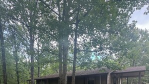 A cabin with a covered porch, a deck, and a staircase leading to a second level. - Cozy 2-bedroom cabin with WiFi, AC in charming Murfreesboro on Lake Greeson. (Murfreesboro)