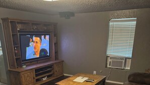A living room with a wooden entertainment center, a television, a coffee table, and two couches. - Cozy 2-bedroom cabin with WiFi, AC in charming Murfreesboro on Lake Greeson. (Murfreesboro)