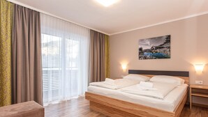 A hotel room with a large bed, wooden headboard, and a painting on the wall.
