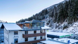 A modern hotel with multiple floors, a covered parking area, and a view of a snowy mountain.
