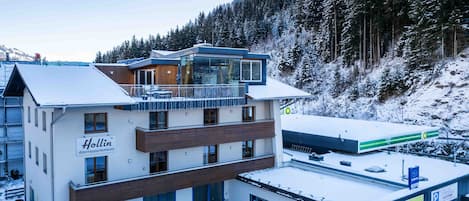 Un hotel moderno con varios pisos, una zona de estacionamiento techada y vistas a una montaña nevada.