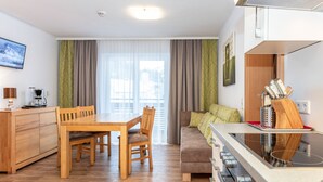 A modern kitchen with a dining area, wooden furniture, and a built-in oven.