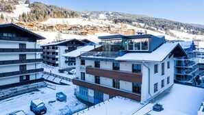 Un hotel moderno con varios pisos, balcones y vistas a un paisaje montañoso nevado.