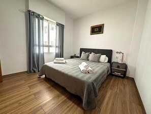 Cozy retreat with a large bed, bedside table, and decorative piece above.