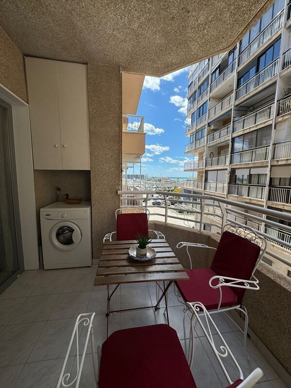Enjoy the marina view from this balcony with a table, potted plant, and two comfortable chairs.