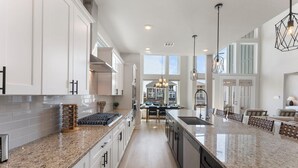 A spacious kitchen with granite countertops, white cabinetry, and a central island. - Lux Lakefront with Game-room, Community Pool, Paddleboards, and more! (Willis)